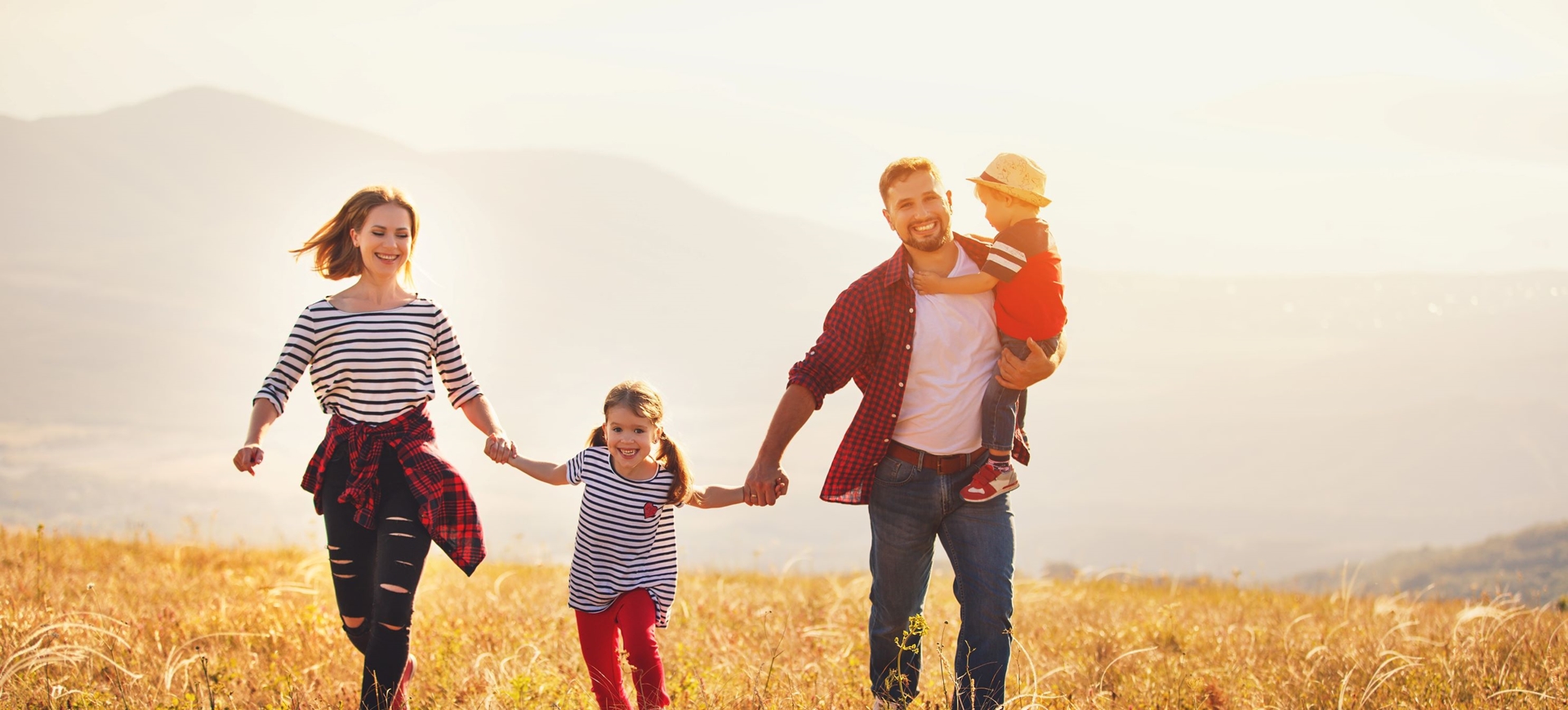 family holding hands and running through field